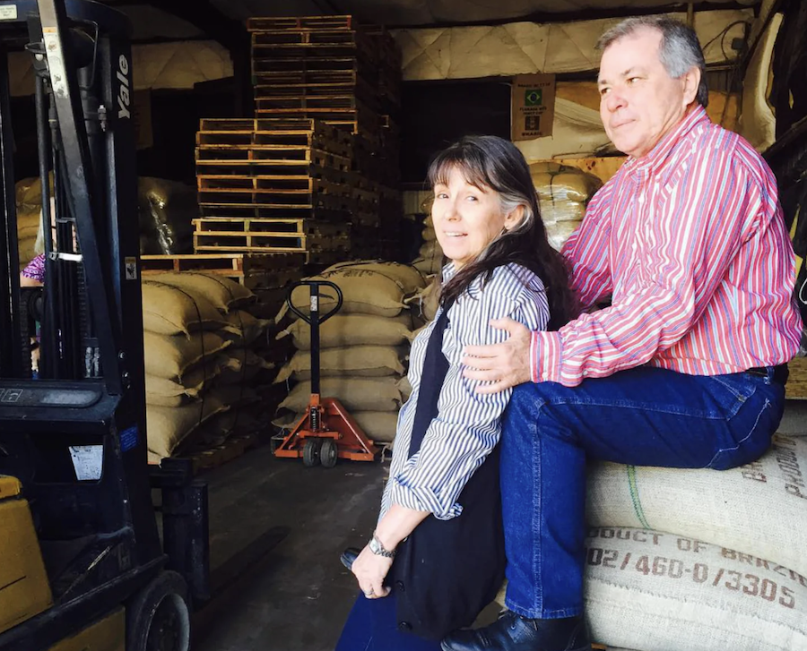 Copan Trade founders Sheri and Walter Dunaway among bags of green coffee at their warehouse